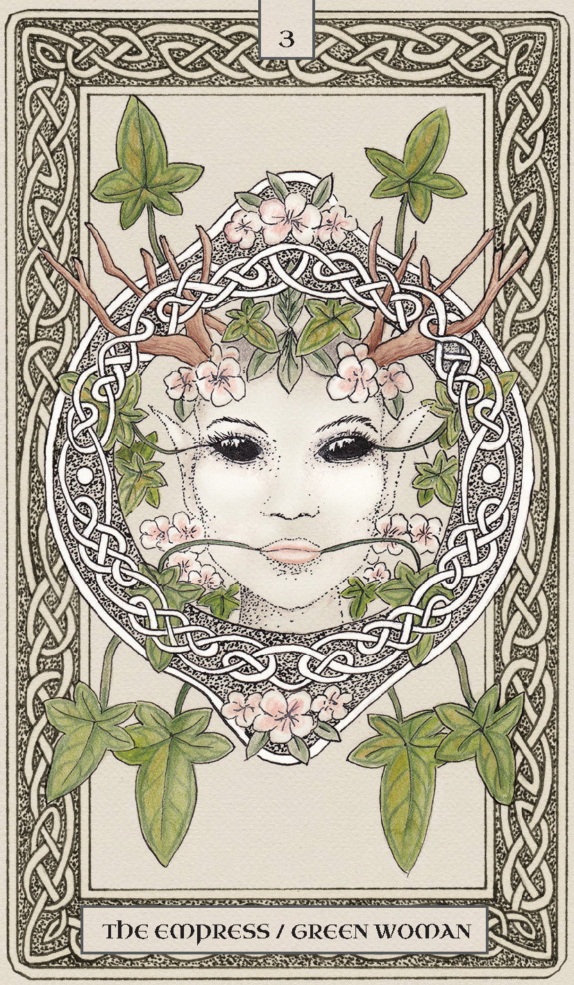 Tarot card featuring a stylized face with antlers and greenery, framed by intricate patterns.