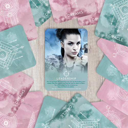 Card with a woman's face surrounded by oracle cards on a wooden surface