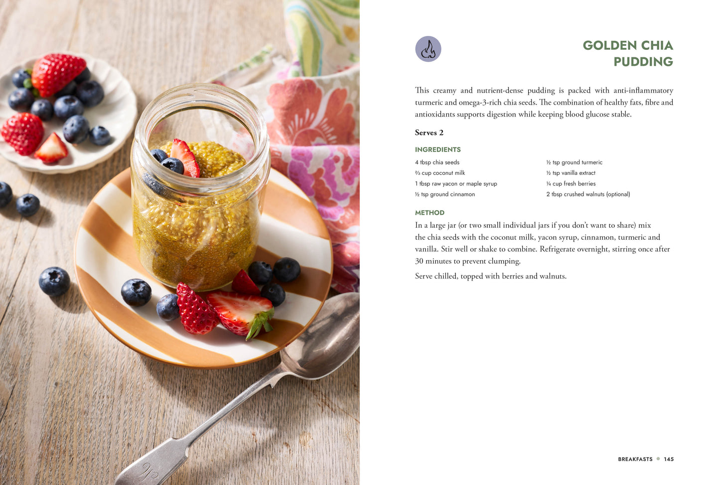 Glass jar of golden chia pudding with berries on a wooden table, next to a recipe card for Golden Chia Pudding.