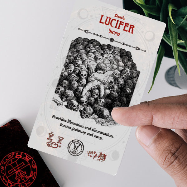 Card with 'Lucifer' and skull design held by a hand on a light background